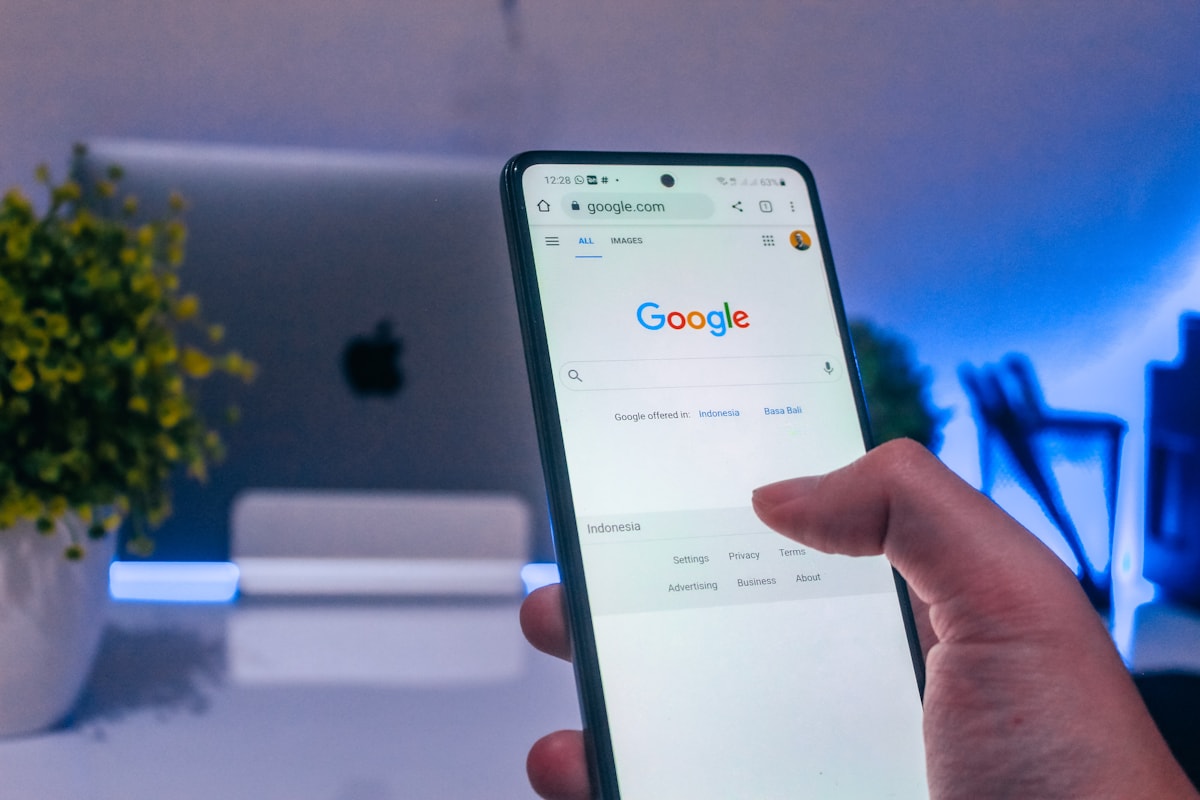 A hand holding a phone open to Google search